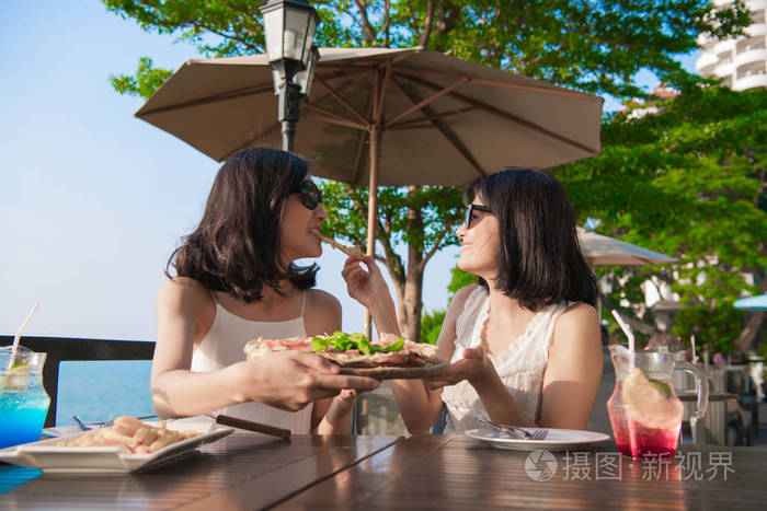 休闲概念美丽的女孩正在海边餐馆吃饭美丽的女孩正在享受桌子上的食物