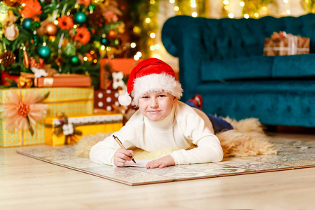 s red cap writes a letter to Santa Claus for Christmas indoors