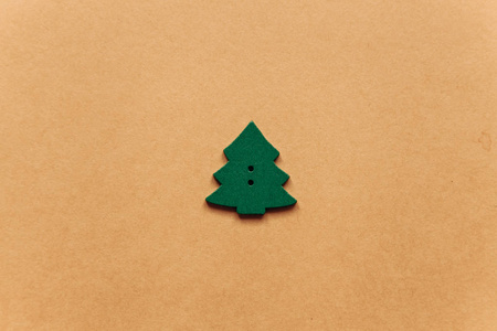 黄色背景上圣诞树的木制绿色玩具。 极简主义。