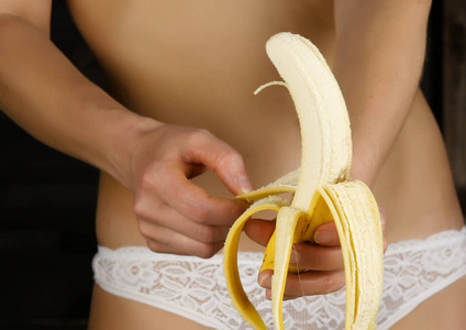 穿着白色内裤剥去香蕉的年轻女子。特写臀部和臀部