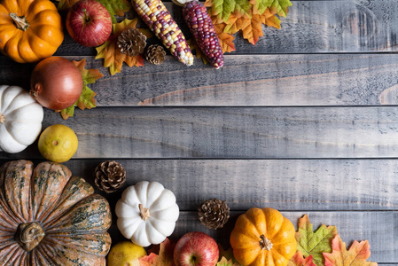 秋天枫叶的顶部视图与南瓜，苹果玉米和红色浆果在旧的木制背景。 感恩节的概念。