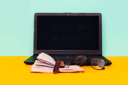 带笔记本电脑眼镜时钟和笔记本的工作台