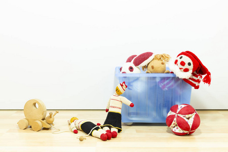 可爱有趣的老式儿童玩具在一个蓝色塑料盒子前面的白色墙壁。 品种包括一个小丑，一个兔子木偶，一只松鼠，一只木蜗牛和一个球。