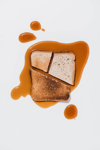 面包片的顶部视图，烤片放在白色表面溢出的棕色糖浆上