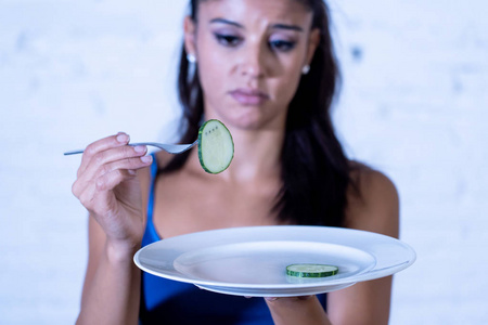 在饮食失调和减肥概念中，年轻有魅力的女人对不想吃蔬菜或健康食物感到悲伤和无聊。