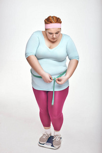 胖乎乎的女人正在测量她的腹部在白色的背景
