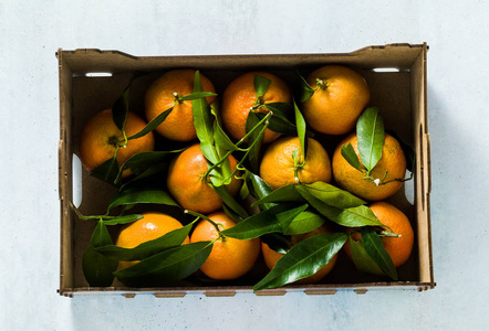 新鲜柑桔水果或橘子，木箱内有叶子，俯视