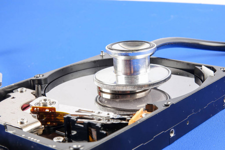 恢复和修复技术概念硬盘驱动器HDD与听诊器隔离在蓝色背景上