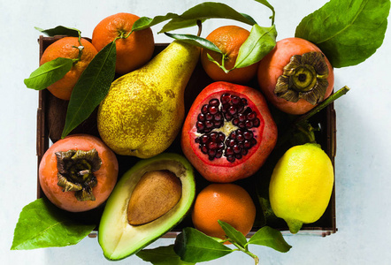 不同水果的石榴梨，柑桔，柠檬，鳄梨和柿子，椰子在桌子上。 木箱内健康营养和每日果汁的基础