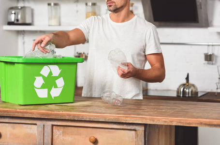把塑料瓶放进绿色回收箱里的人