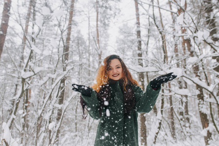 穿帽子和毛衣的女孩在森林里玩雪