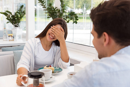积极夫妇喝茶令人惊叹的年轻情侣坐在咖啡馆里吃甜点,喝茶互相交谈.