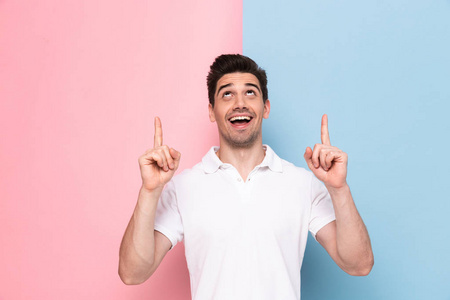 快乐的30岁男人的形象,有胡茬,手指向上指向在五颜六色的背景上被隔离