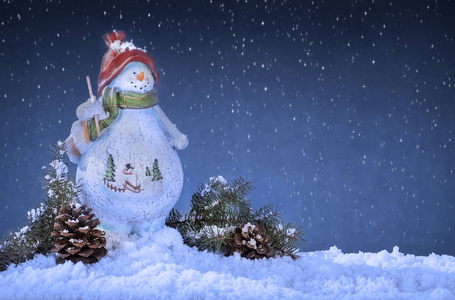 雪人装饰着松果和树枝在雪地上和一个古老的夜晚背景