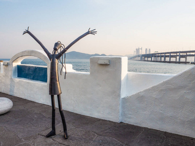 韩东长廊上的金属雕塑,在日落时分在韩国釜山的背景下,以万安桥为背景