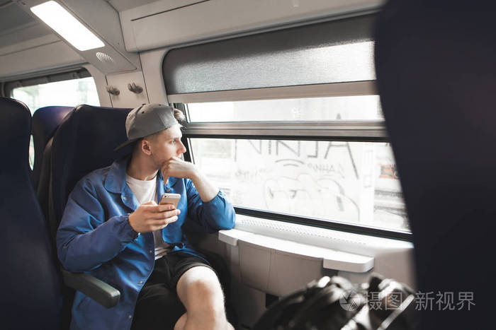 抱着智能手机的学生坐火车去看窗户.