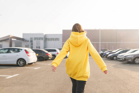 s back in a yellow hoodie, walking along the street. Lookbook. S