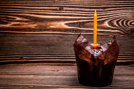 节日巧克力松饼与橙色蜡烛在木制表面。