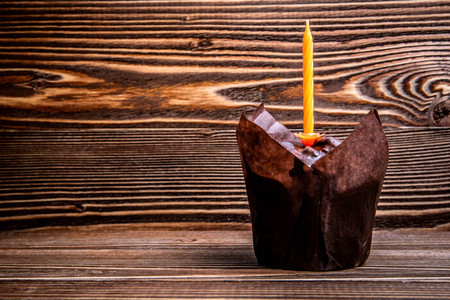 木制表面上有蜡烛的节日巧克力松饼。
