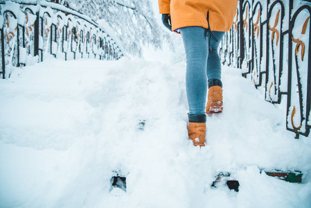 女人走在下雪的城市公园小桥上，穿过冰冻的河流概念