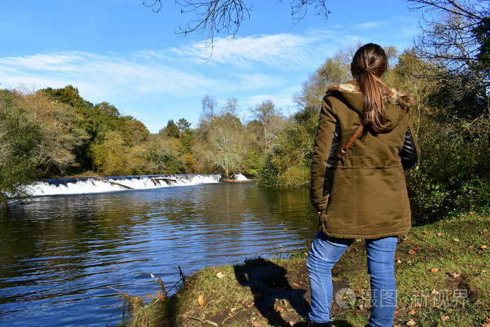 森林里的女人看着风景秋天的颜色是树木河流和瀑布蓝天和云彩