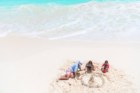 查看从上面给父亲和小女儿做沙子城堡在热带海滩