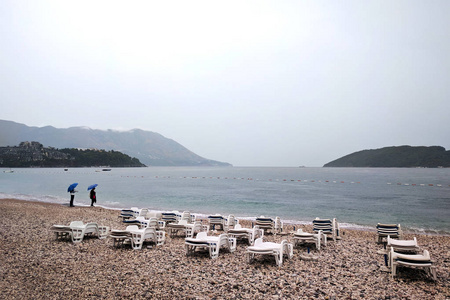 亚得里亚海附近一片荒芜的海滩上的秋雨。 伞下的人。 九月在黑山。