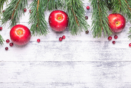 有树枝红苹果和蔓越莓的圣诞节背景。轻木桌。降雪画效果..上景。复制空间
