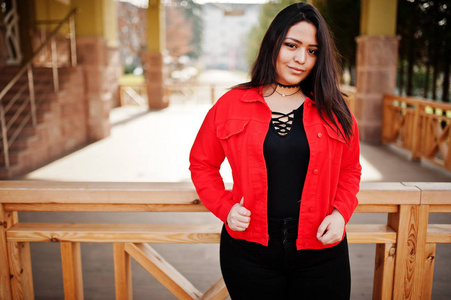 来自厄瓜多尔的漂亮拉丁模特女孩穿着黑色和红色夹克在街上摆姿势。