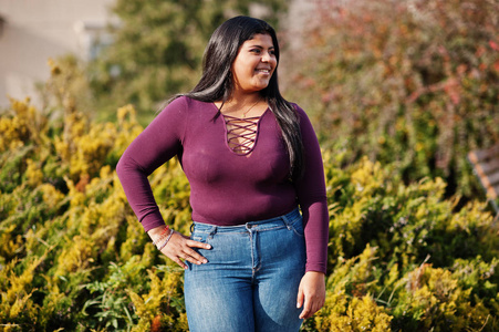 来自厄瓜多尔的漂亮拉丁裔xxl模特女孩穿着紫罗兰色的衬衫在街上摆姿势。