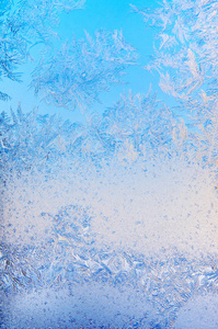 在圣诞节的特写镜头中，窗玻璃上冰冷的冬日午后，冰晶的蓝色纹理图案
