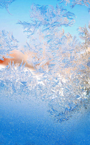 在圣诞节特写镜头中，在寒冷的冬天，窗玻璃上的冰冻水晶的蓝色纹理图案