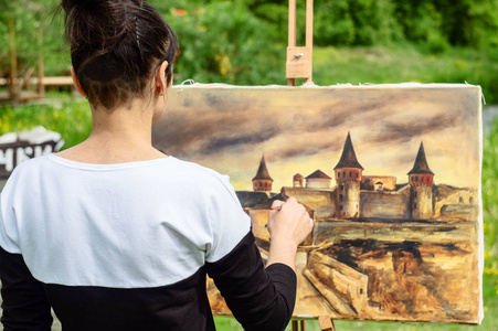 年轻女孩艺术家在工作。 画一幅画。 一座古老的乌克兰堡垒