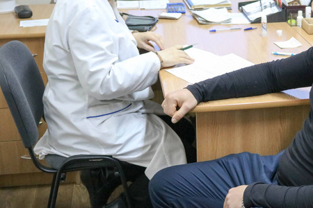 医生, 穿着白色外套的医务人员建议病人坐在医疗机构的椅子上