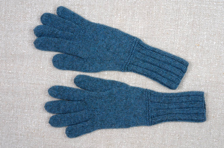 织物背景上的蓝色手工手套。 从上面看。