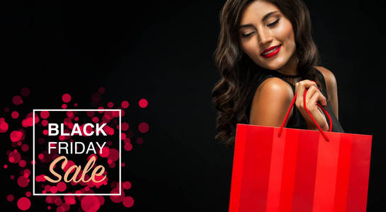 黑色星期五销售理念。购物妇女举行红色袋子孤立在黑暗背景假日