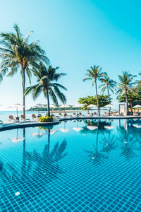 美丽的热带海滩和大海，在酒店度假胜地的游泳池周围有雨伞和椅子，供旅行和度假使用