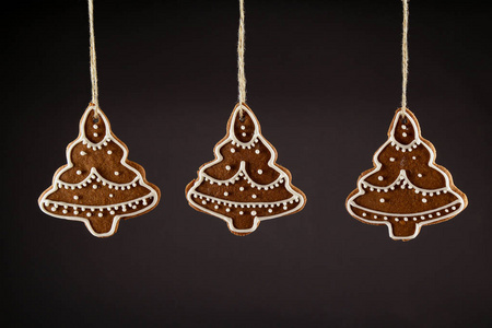 圣诞姜饼饼干圣诞树挂在黑色背景上的绳子上。 圣诞节背景