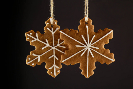 圣诞姜饼饼干雪花挂在绳子上的黑色背景。 圣诞节背景