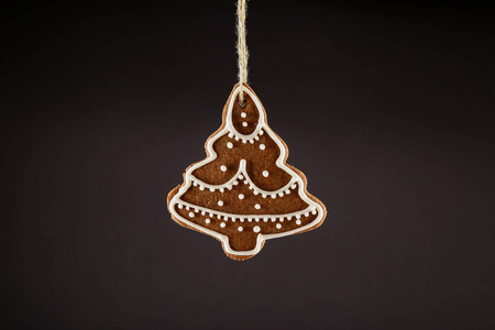 圣诞姜饼饼干圣诞树挂在黑色背景上的绳子上。 圣诞节背景