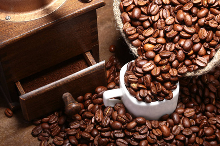 新鲜的烤咖啡豆在麻布袋，咖啡杯，磨床在黑暗的背景