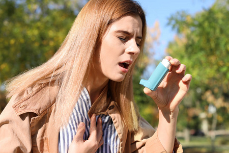 在户外使用哮喘吸入器的女人。 保健