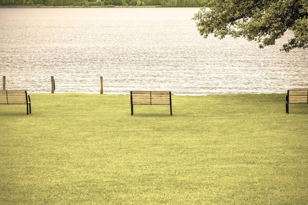 在奥地利农村景观中,一个小的有井的公园,在一个湖边的草坪上有长凳.