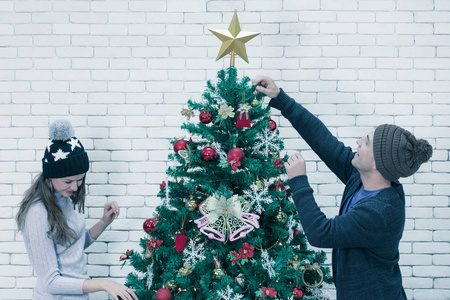 年轻貌美的卡考西夫妇在庆祝的时候一起装饰圣诞树
