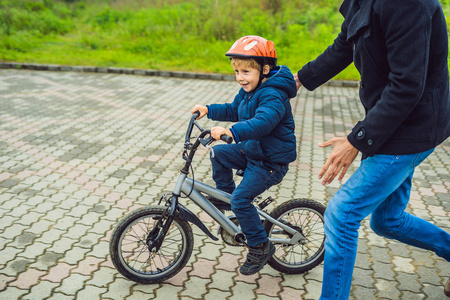 父亲在公园里教小男孩骑自行车。