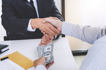 贿赂和腐败的概念,以美元票据的形式贿赂,商人握手和给予隐藏的钱