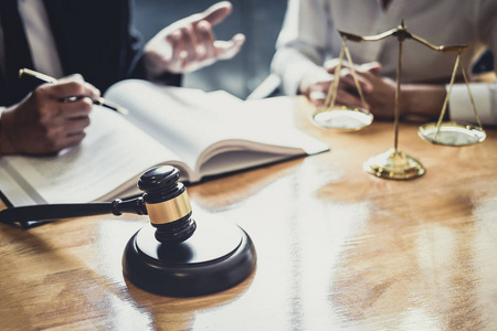 在法庭工作的男性律师或律师与客户会面，与房地产法律和法律服务概念的合同文件进行协商。