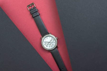 s fashion wrist watch on red background. Two black sheets soar a