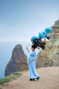 穿着蓝色长裙带气包的孕妇摆姿势