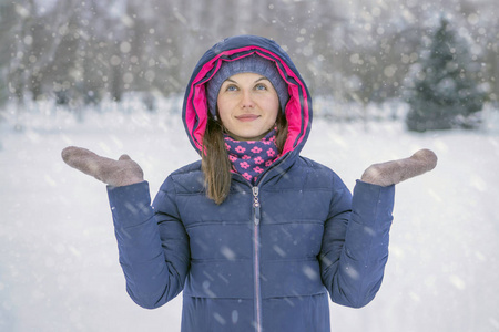 年轻美丽的微笑的女人用手接住雪花。 冬天下雪天气